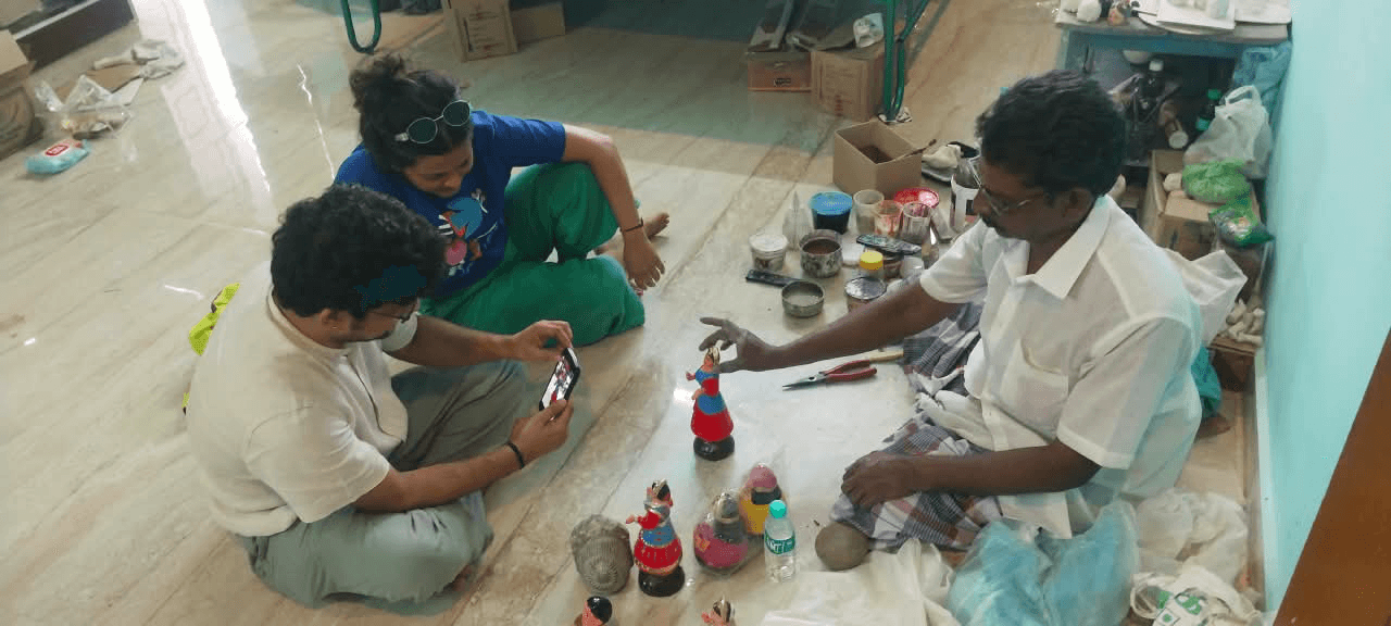 Artisan showing a finished dancing doll to travellers