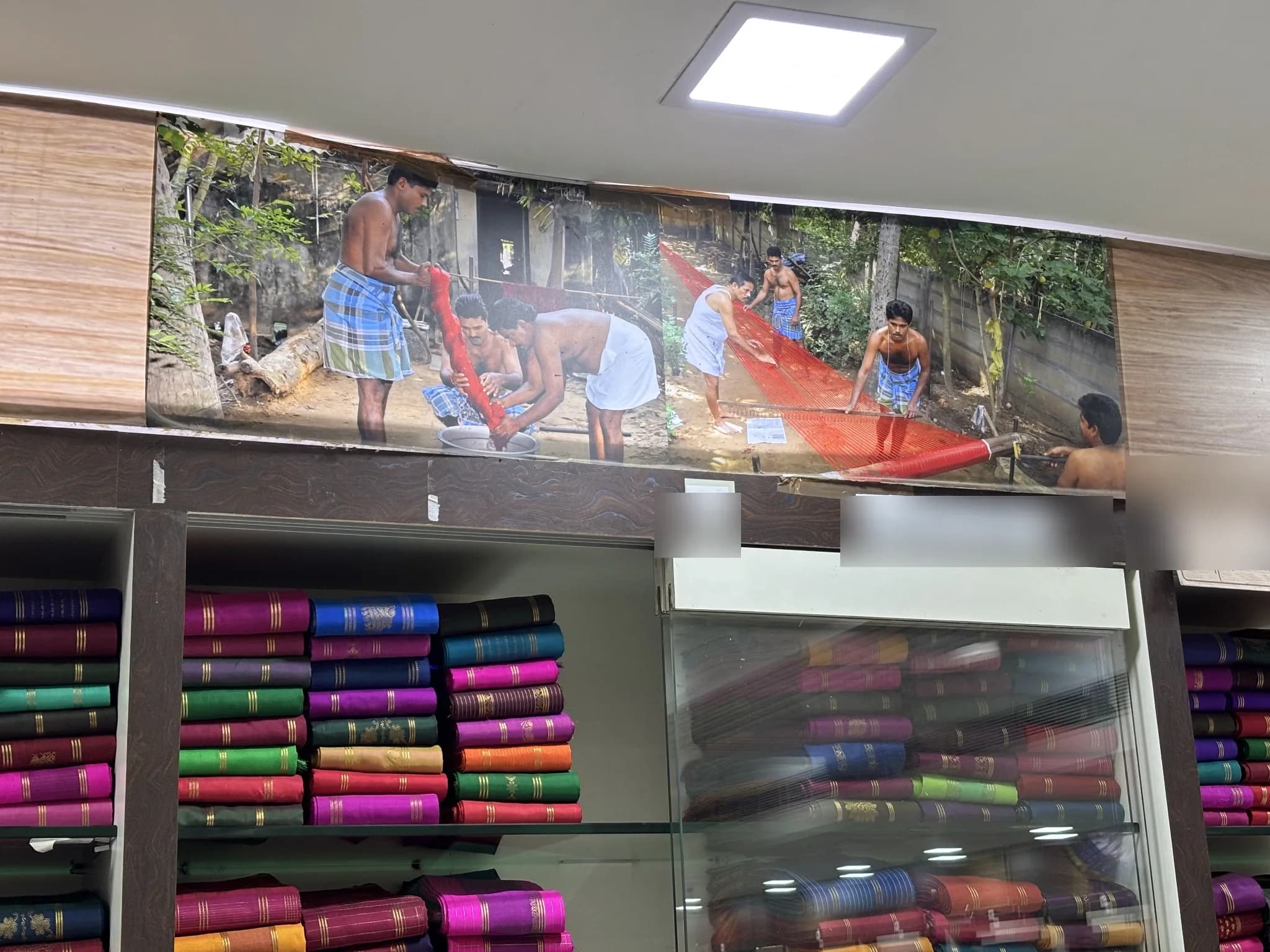 Shelves of finished Thirubhuvanam silk sarees beneath a mural of the dyeing craft